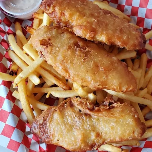 Three pieces of golden-brown fried fish and a pile of french fries in a red and white checkered basket.
